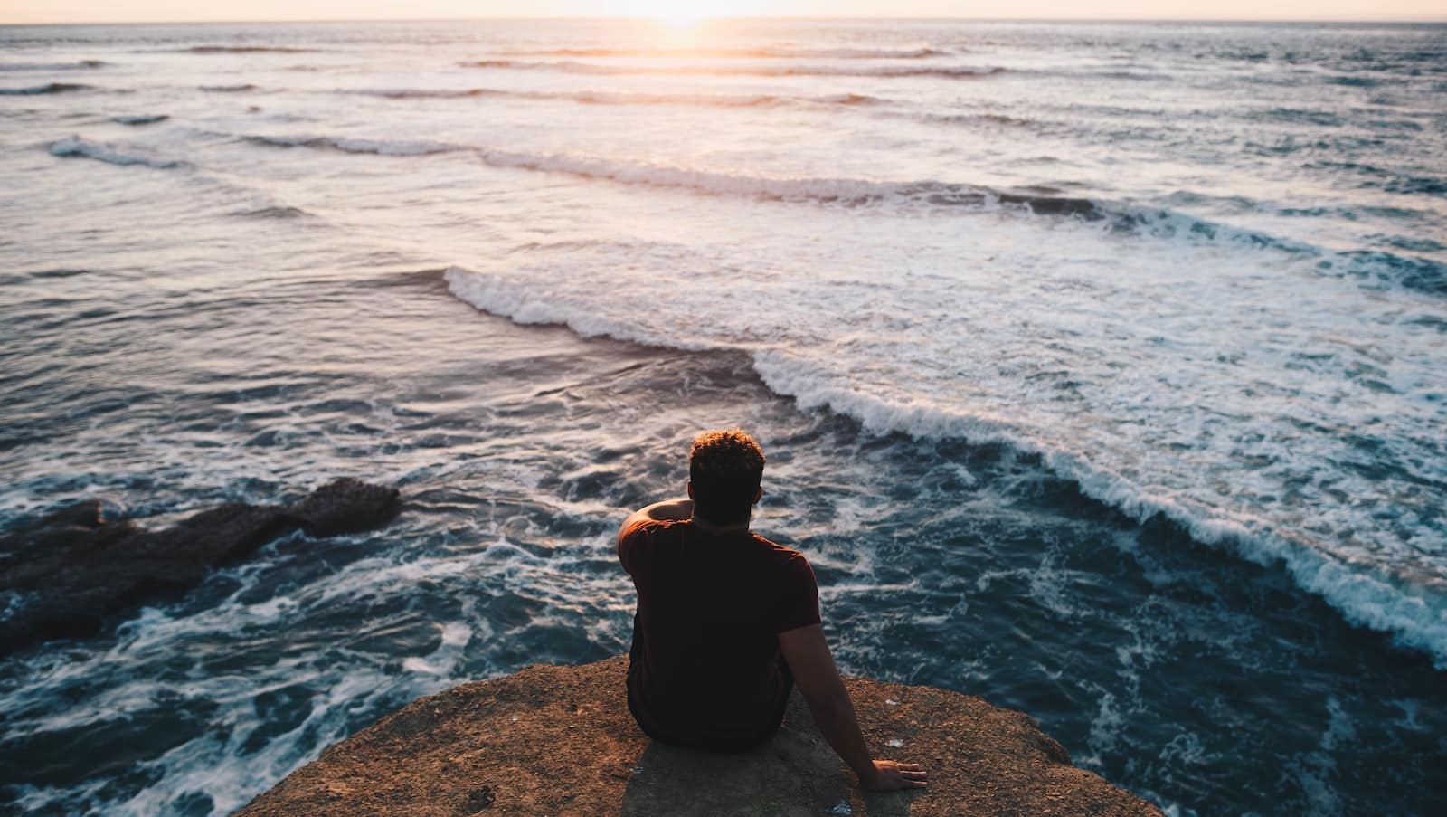 man on cliff overlooking ocean